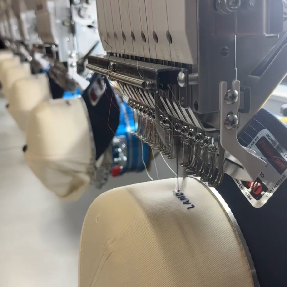 Close-up of a Barudan embroidery machine with a beige fabric sample.